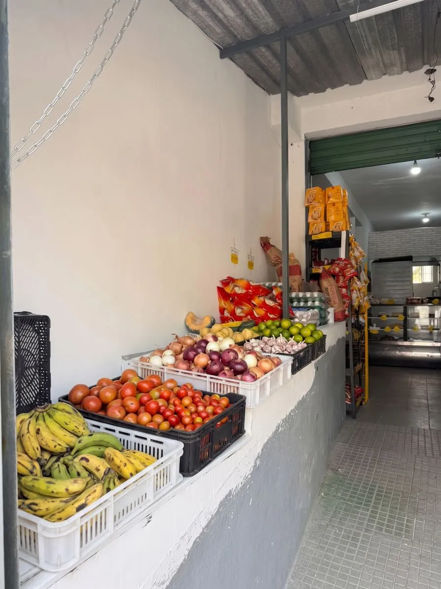 Caixas com banana, tomate, cebola, alho e limão na entrada da loja